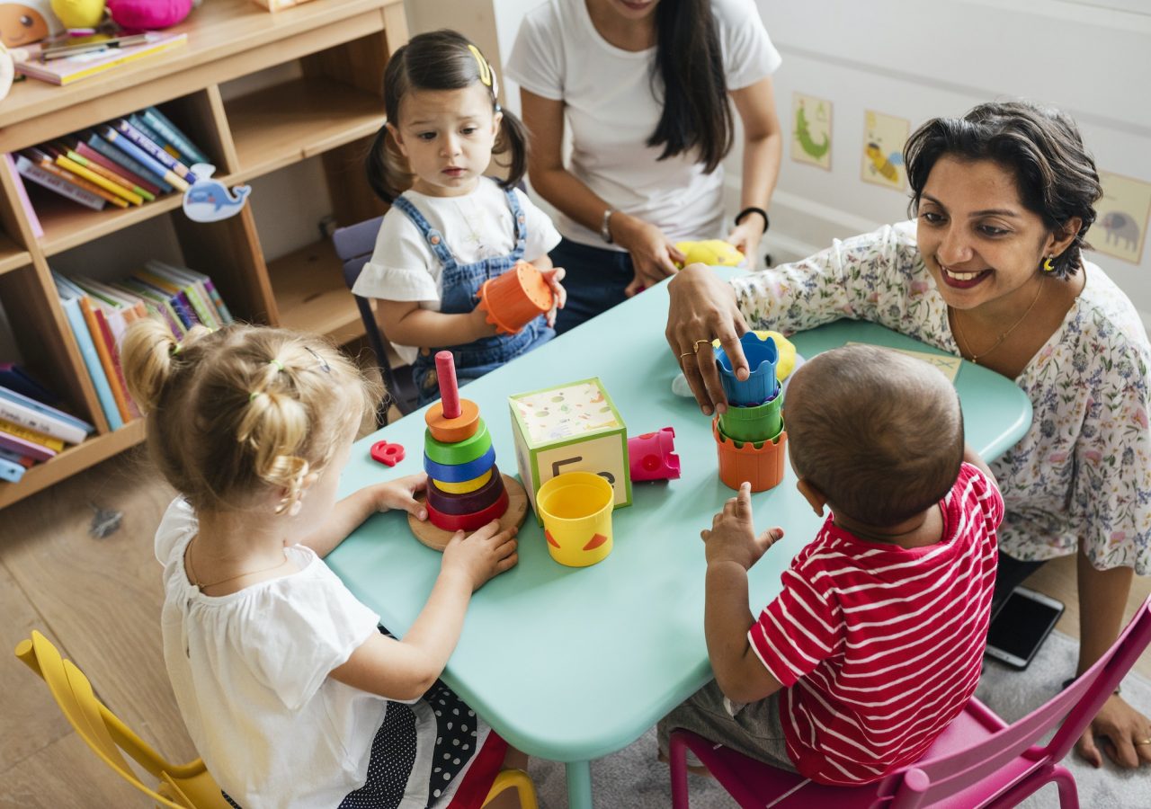 Nursery Children Playing With Teacher In The Classroom.jpg